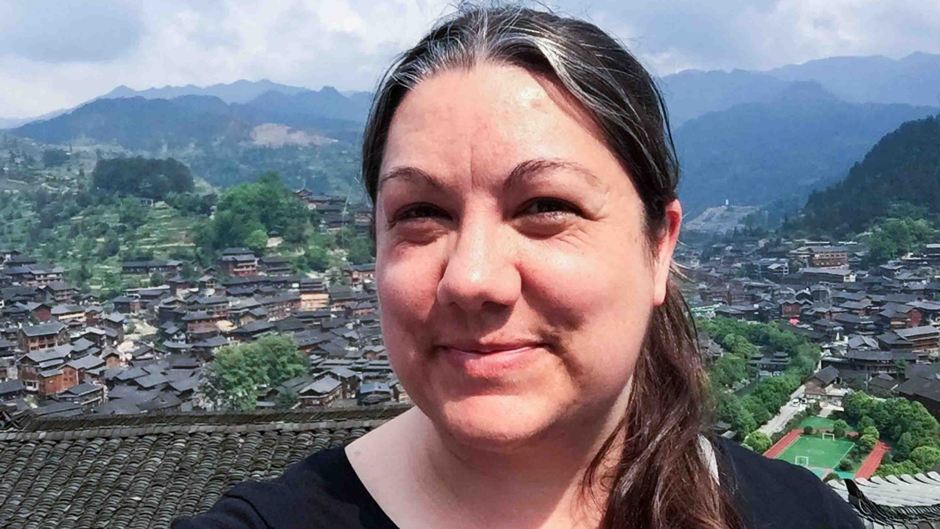 A woman with a valley and houses in the background.