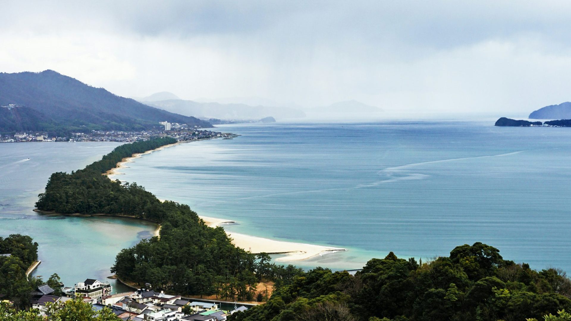 View of green sandbar isthmus running across blue water