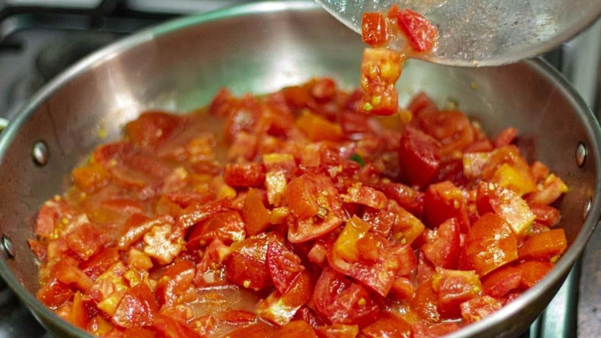 Tomatoes and garlic fried in large silver pot