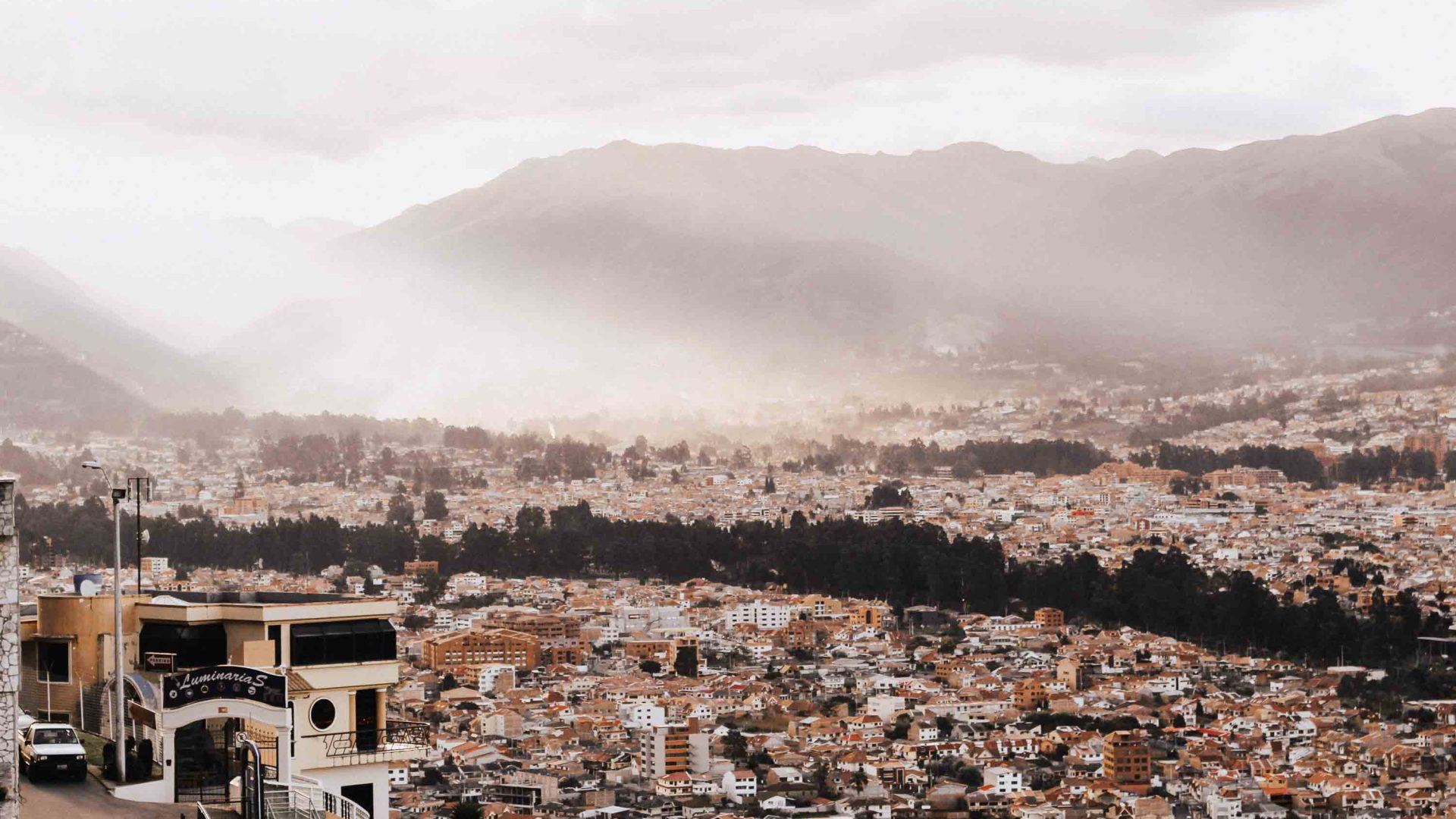 Looking down over a city with mountains in the background and mist settling.