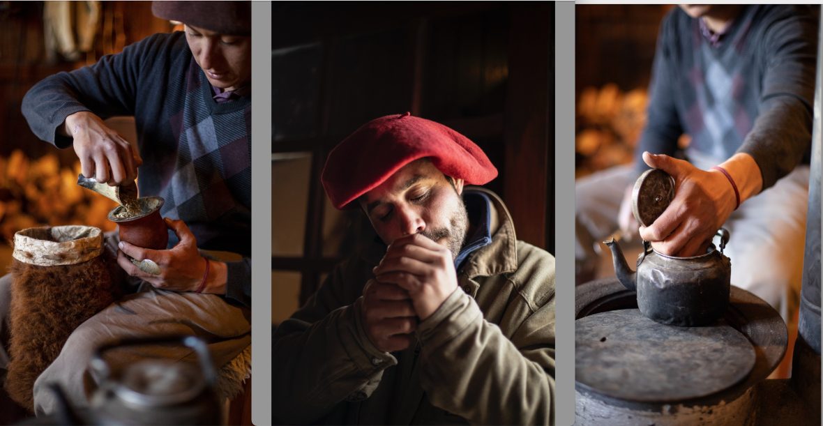 A man smokes and hands can be seen making mate drink.