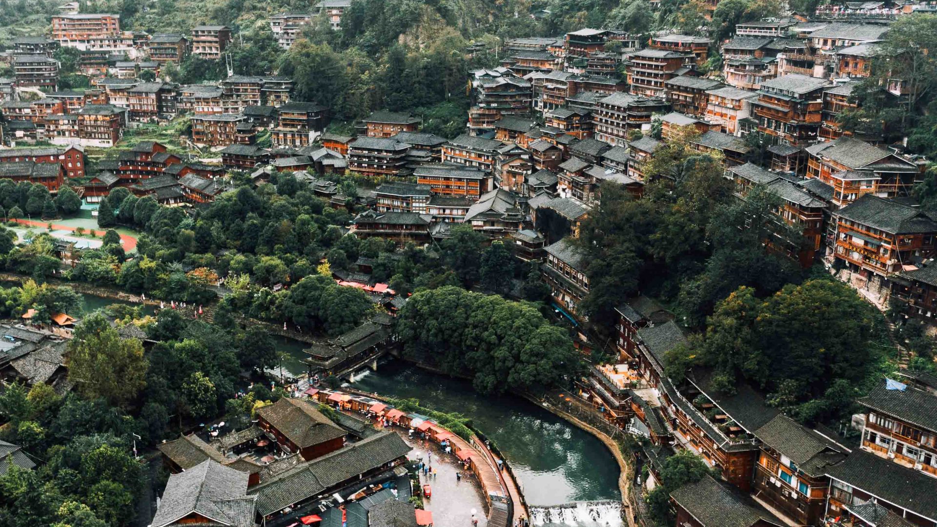 Houses in a green valley lead down to a river.