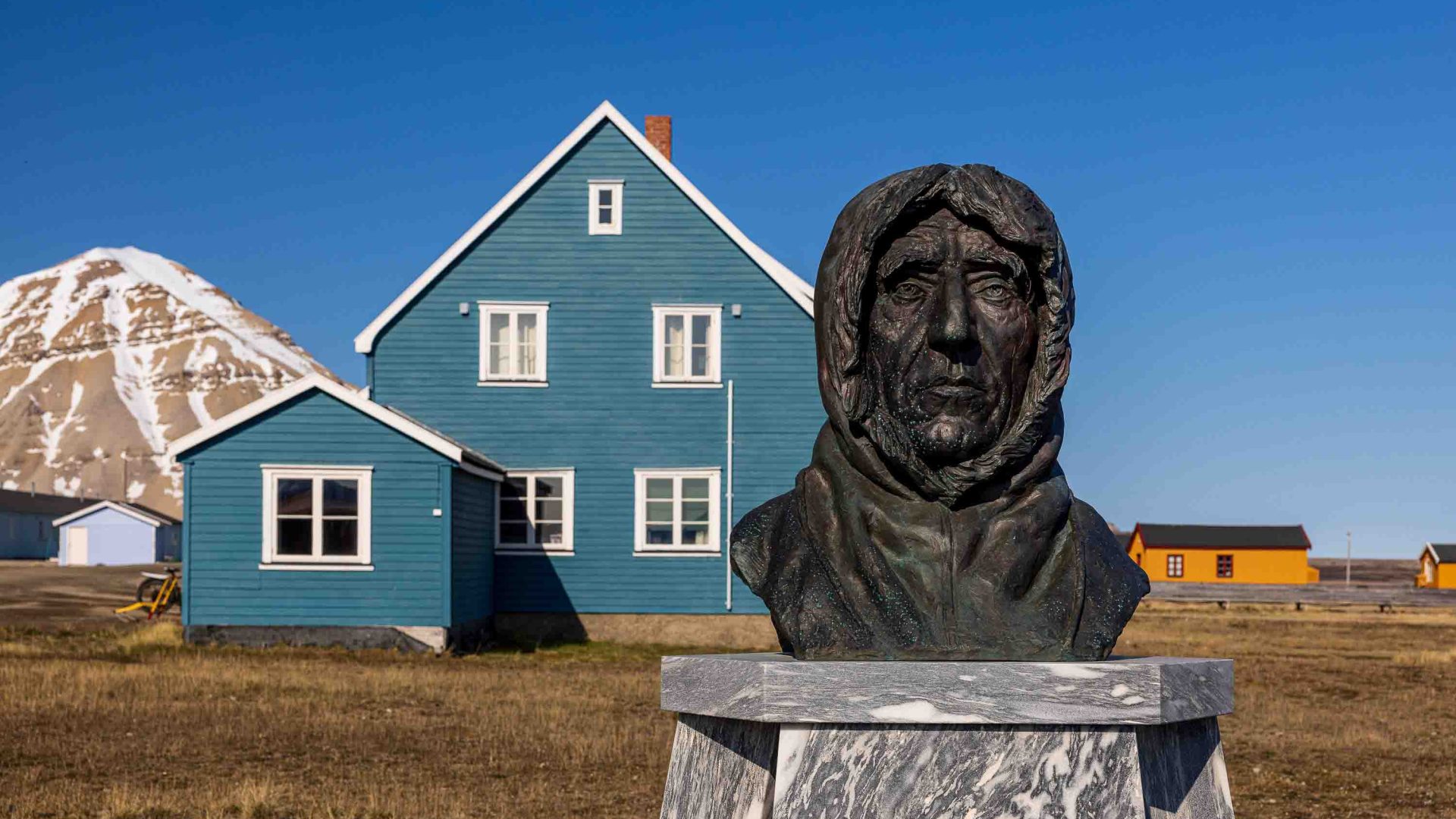 A statue in front of some colourful buildings.