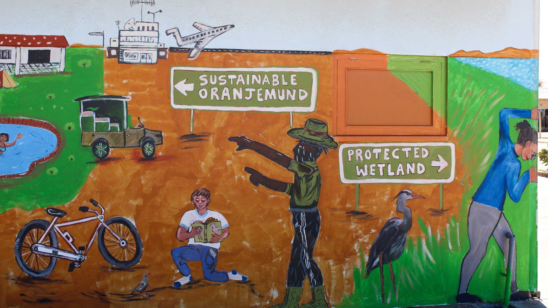 A mural depicting people, wetlands, a plane and a bike.