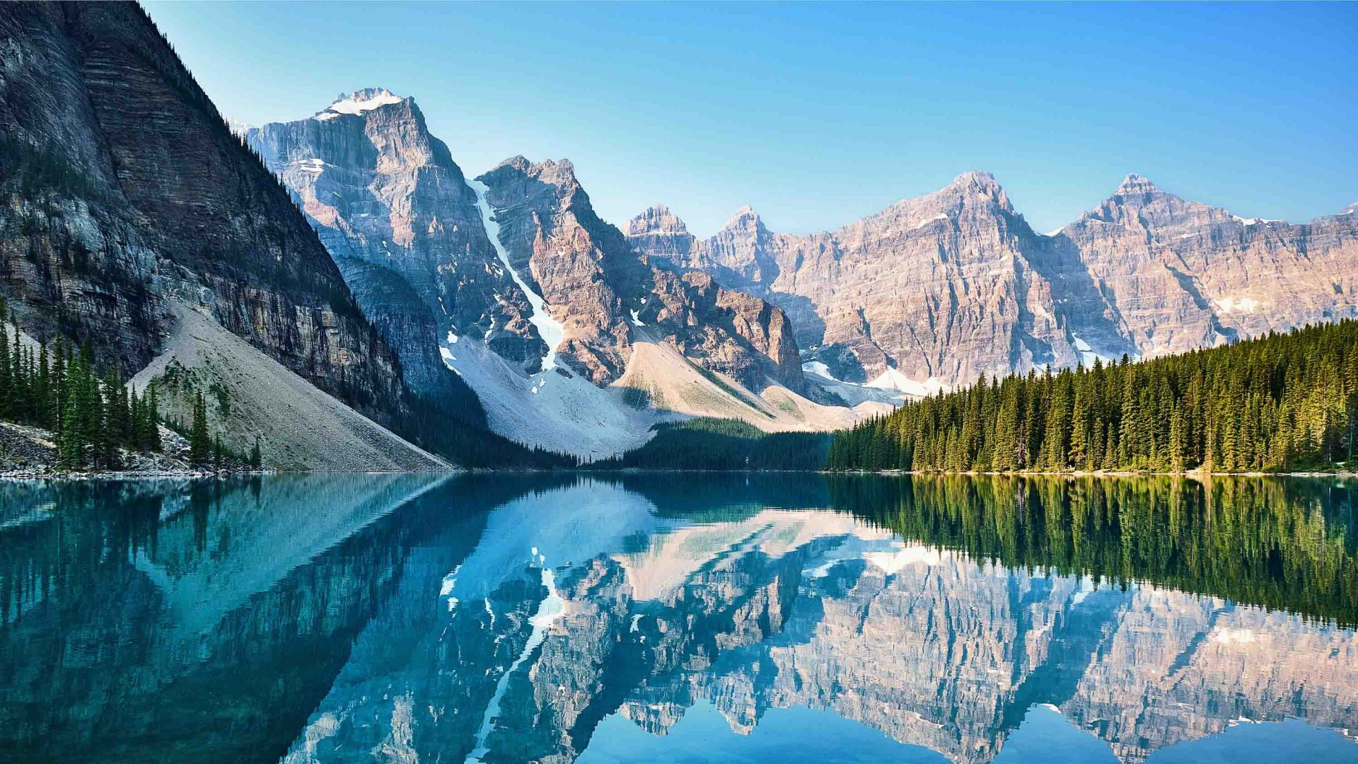Mountains are reflected into the still water of the lake.