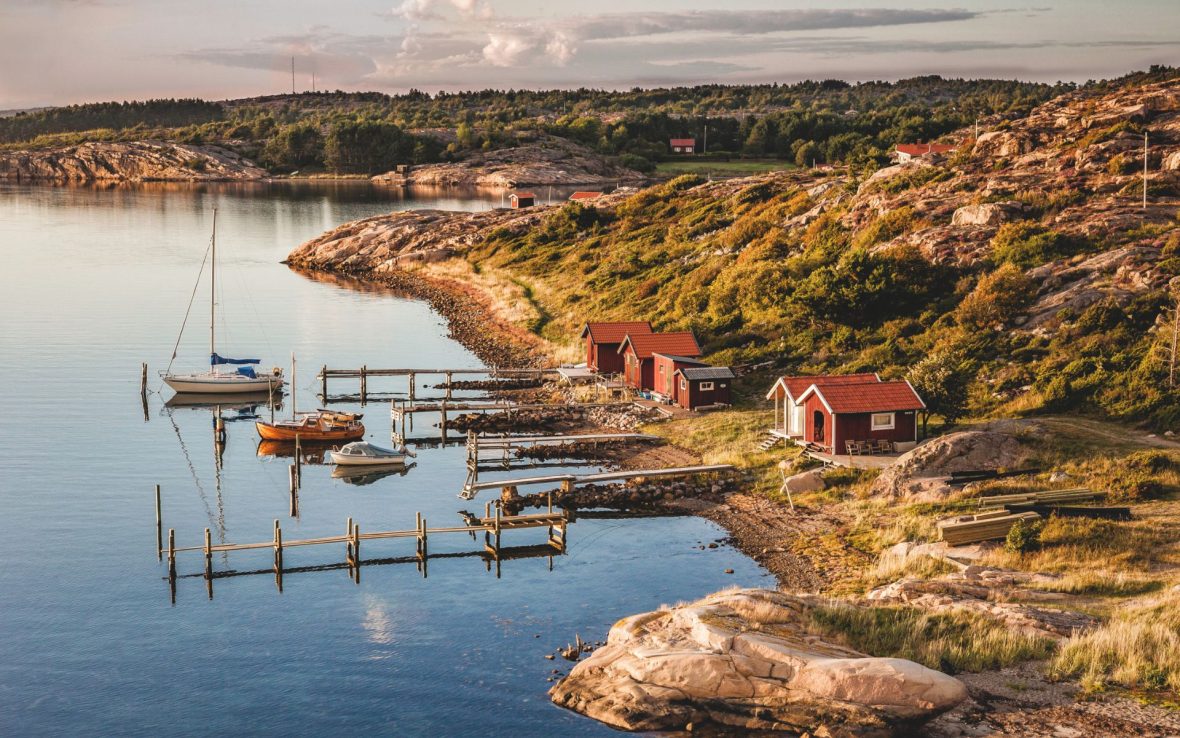 An aerial view of coastal Sweden, with docks extending into the water in front of red houses.