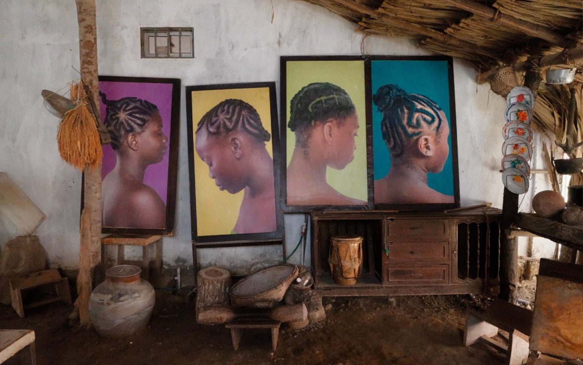Thatched roof room shows four large photographs of Afro-Colombian hairstyles.