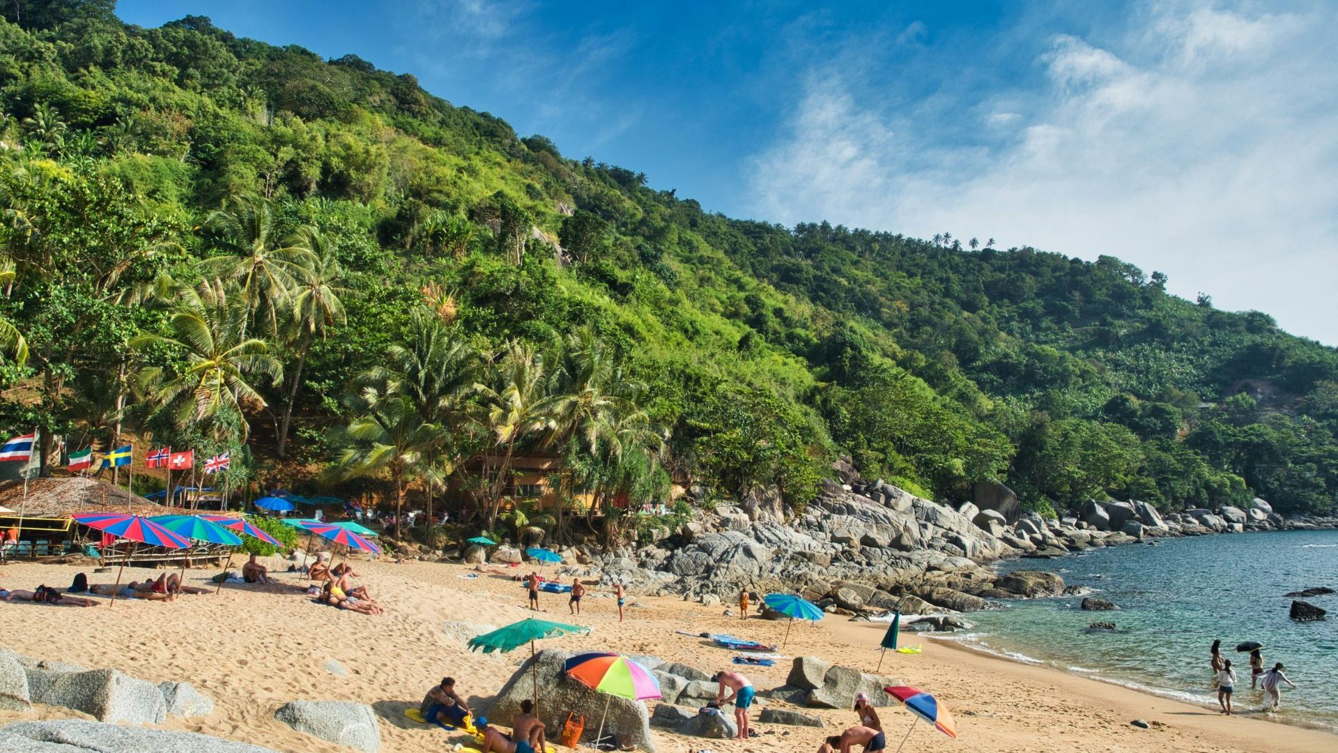 Busy white sand beach full of tourists by the water