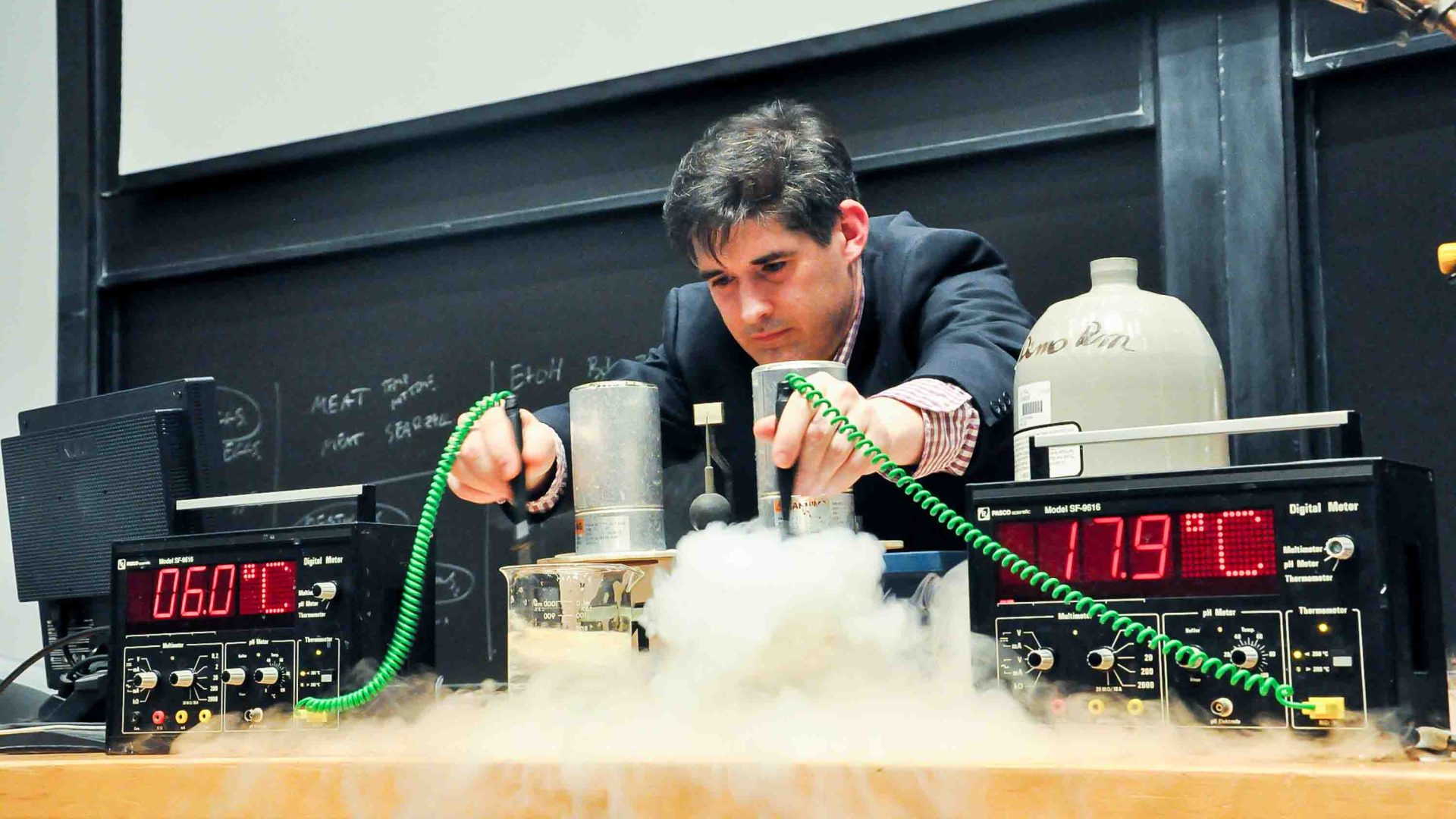 A man does an experiment involving temperature with steam coming out of two jars.