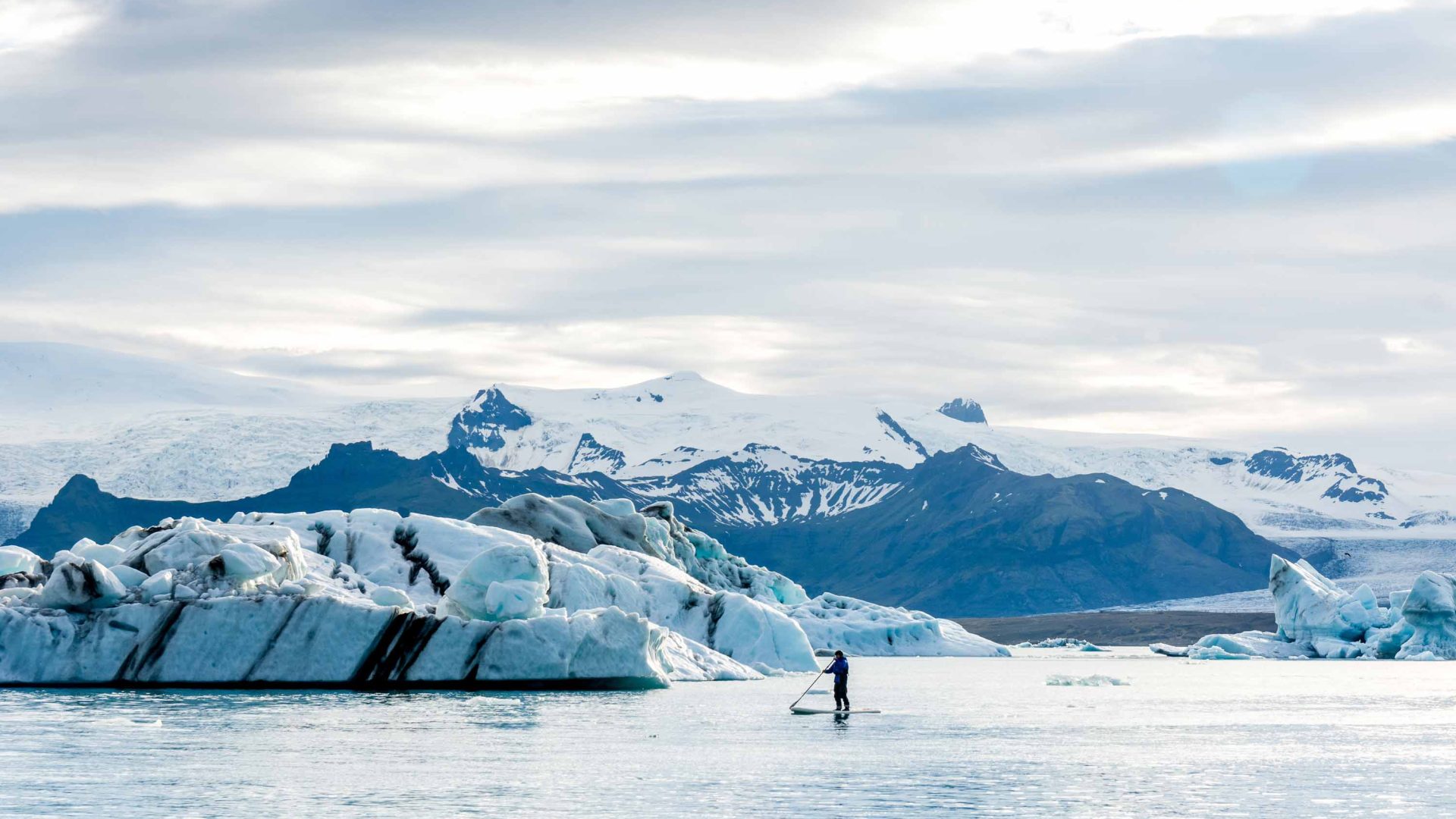 A person does stand up paddle amongst icebergs.