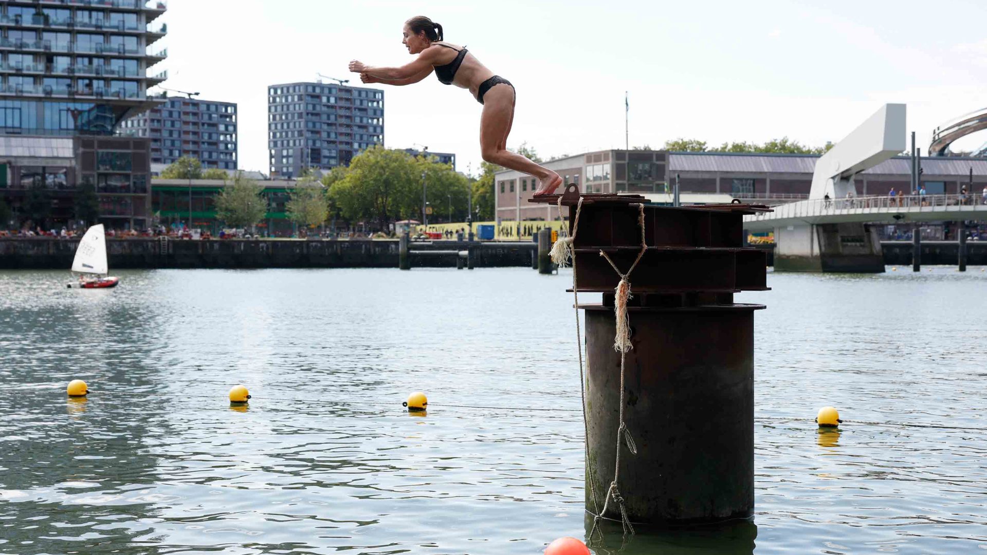 A woman jumps off a platform into a river
