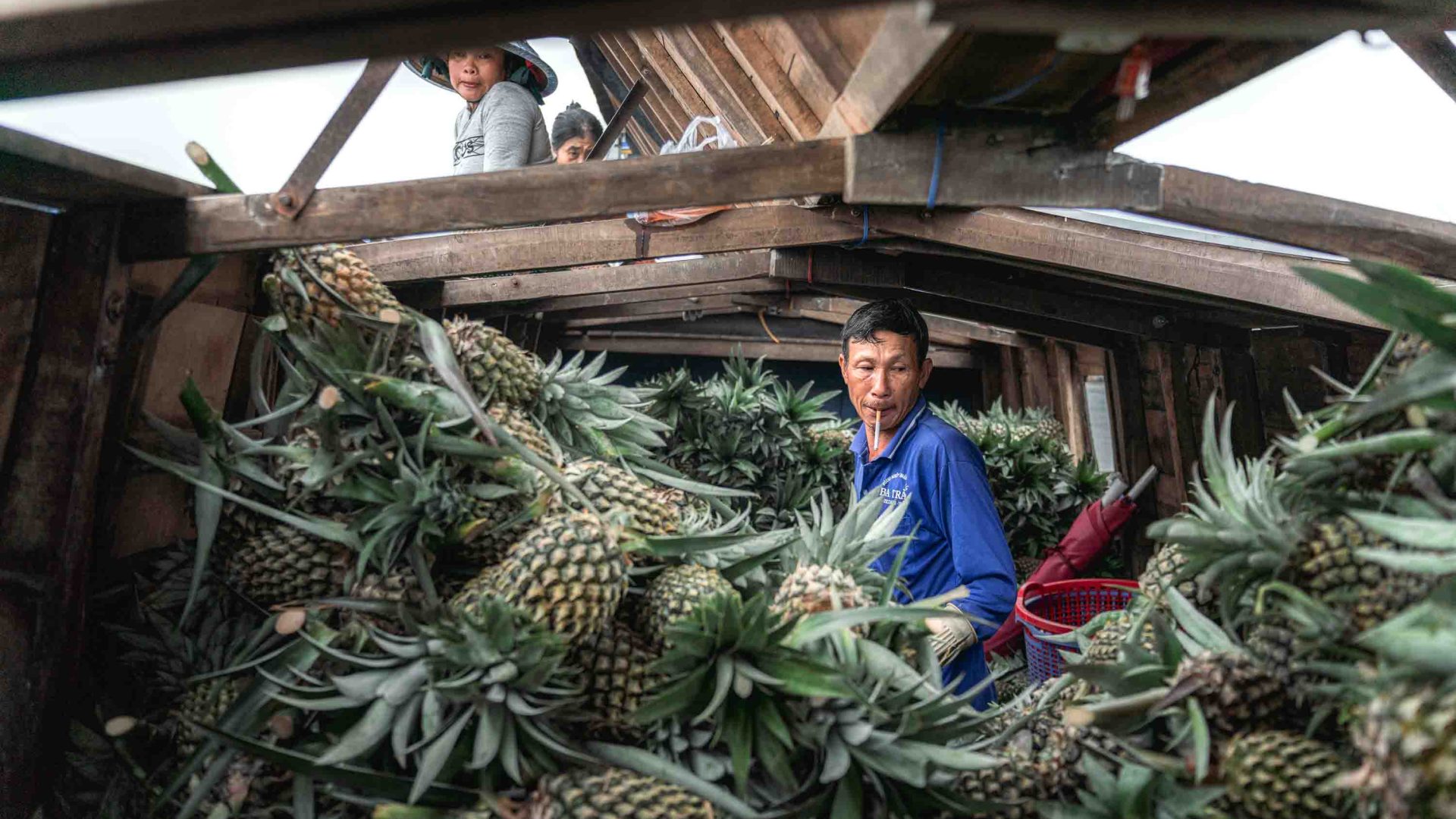 A man is surrounded by pineapples on a boat.